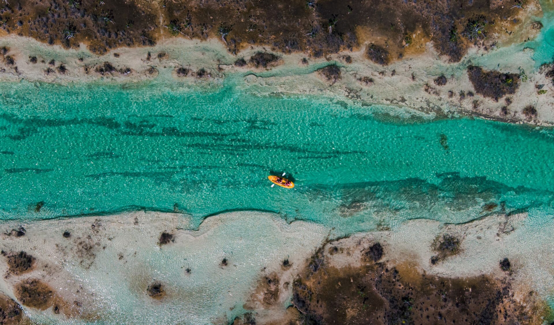 kayaker paddling through the vibrant, turquoise waters of Bacalar Lagoon in Mexico