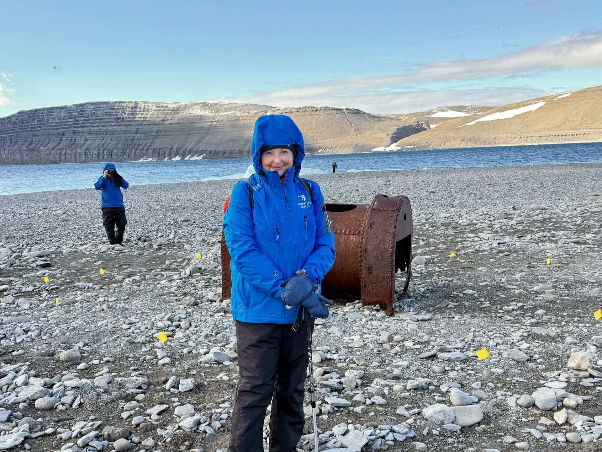 Linda Barnard in Nunavut Linda Barnard in Nunavut, standing on a rocky beach and wearing a blue, branded Adventure Canada winter jacket